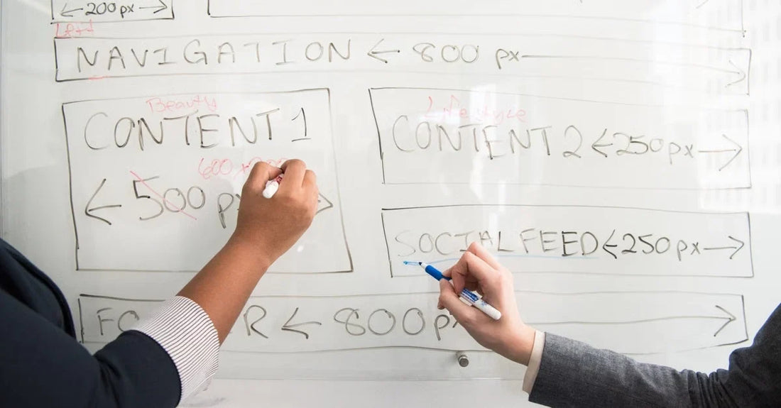 Two hands sketching pillar content strategy wireframe with logo, banner, navigation, and content sections on whiteboard.