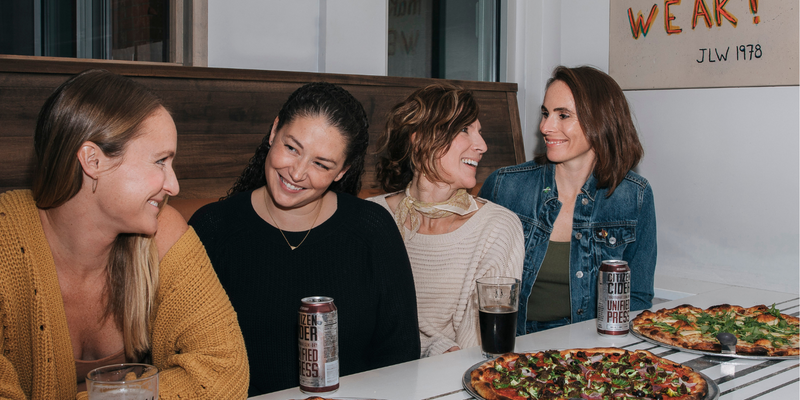 woman smiling together at a pizza place