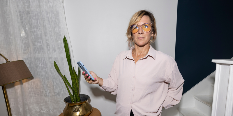 a woman in a pink shirt holding her phone