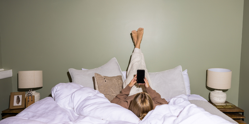 woman laying on her bed on a cellphone