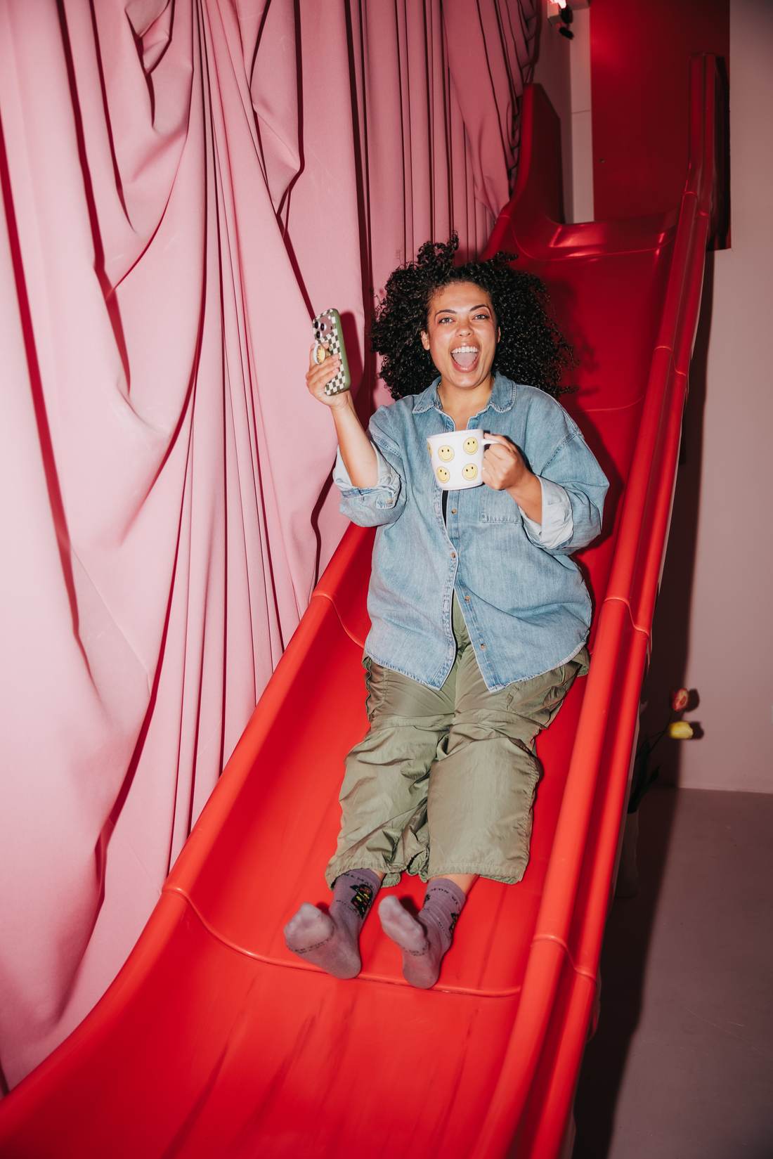 A Strong Brand Social member laughing on a giant red slide, coffee in hand