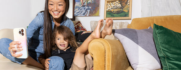 A woman and her son being silly on a couch, taking a selfie